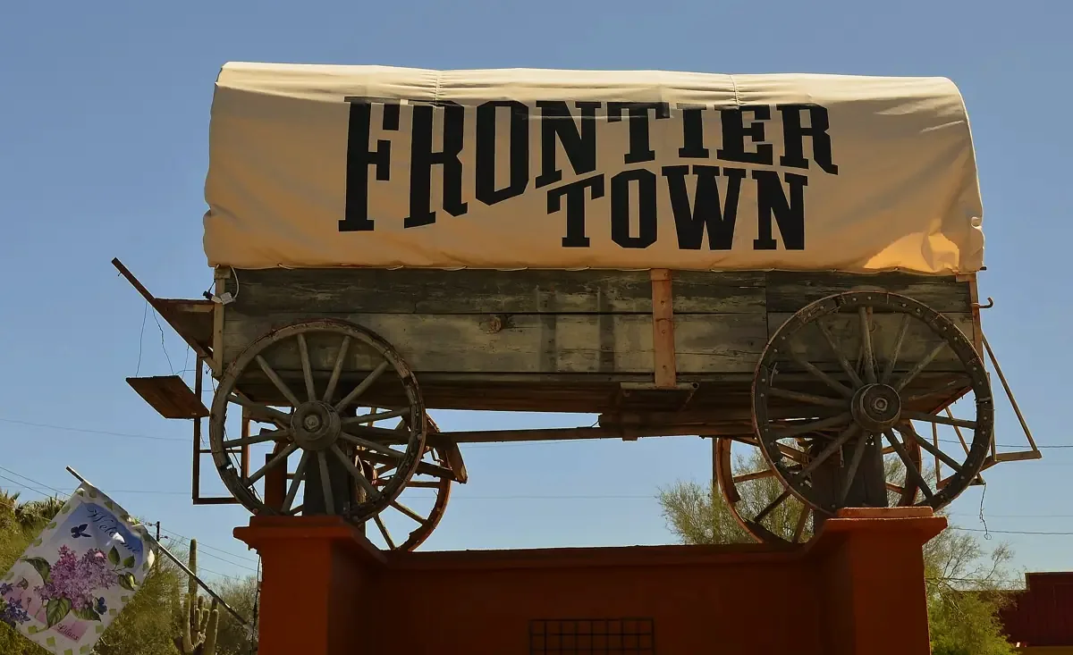Covered-wagon sign at Frontier Town on Cave Creek Road under a blue sky
